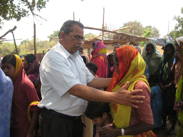 Praying with villagers during an outreach visit