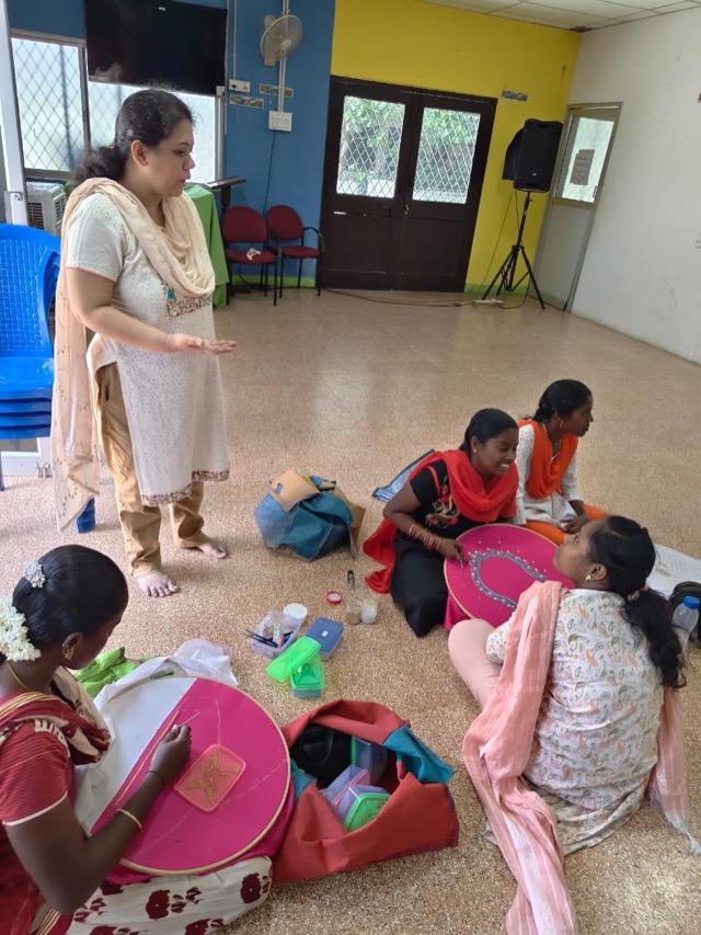 A trainer guiding women in the embroidery class